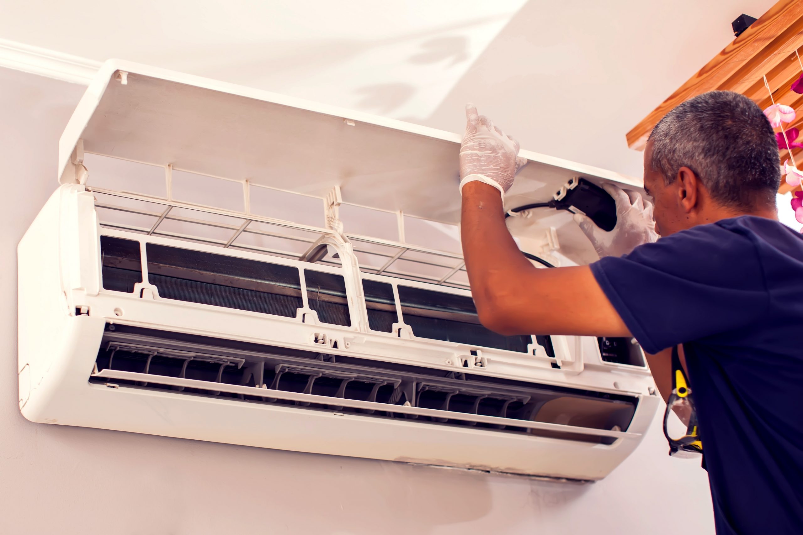 Man worker fixing air conditioning on the wall.