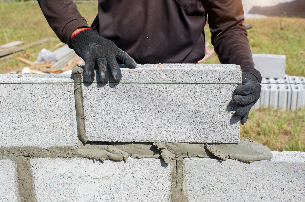 masonry technician adding a brick to a wall with mortar